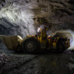 Rotary drills, bulldozer, and excavator operating at a mining site, addressing mining corrosion challenges.