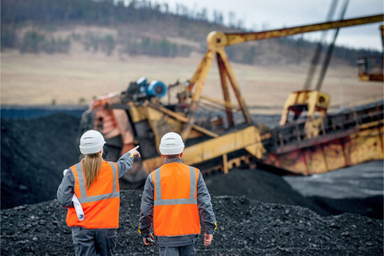 Mining employees at a site with rusted equipment in the background, showing the impact of corrosion on mining equipment.