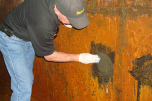 Technician using ZERUST rust remover on a corroded hydroelectric turbine.